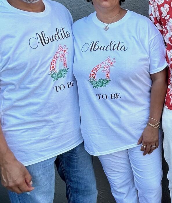 Couple wearing matching white Abuelita and Abuelito To Be shirts