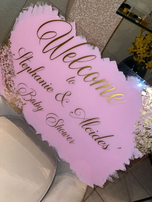 Pink acrylic baby shower welcome sign with gold script lettering