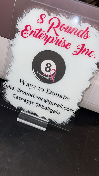 White acrylic donation sign with a pink logo and payment details
